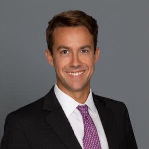 Headshot of Dr. Jason Miles in professional wear with a grey background.