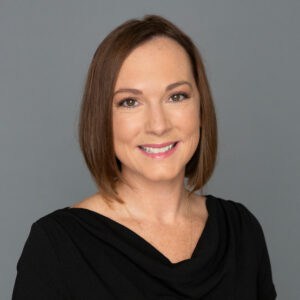 Headshot of Dr. Kimberly Riordan in professional wear with a grey background.
