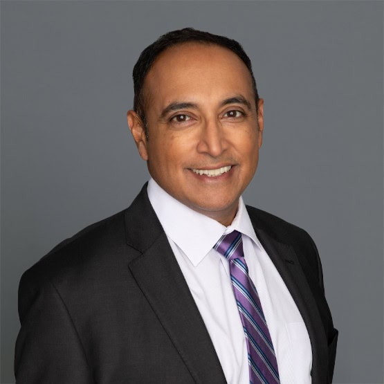 Headshot of Dr. Rajesh Shetty in professional wear with a grey background.