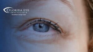 photograph of a blonde women's blue eye. The image has a blue shadow overlay with the Florida Eye Specialists logo in the top left corner.