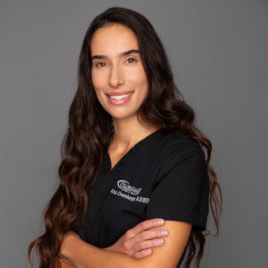 Headshot of Ana Greenberger in professional wear with a grey background.
