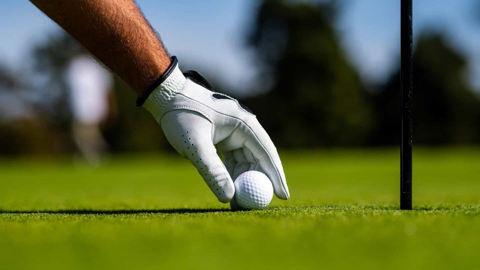 man putting a golf ball down